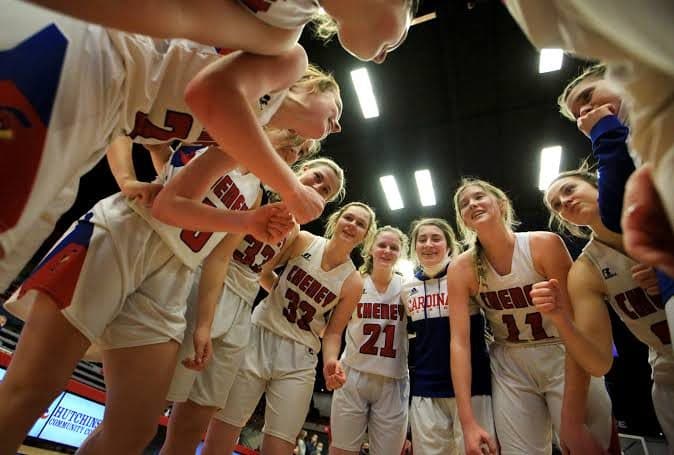 A girls basketball team huddles in celebration