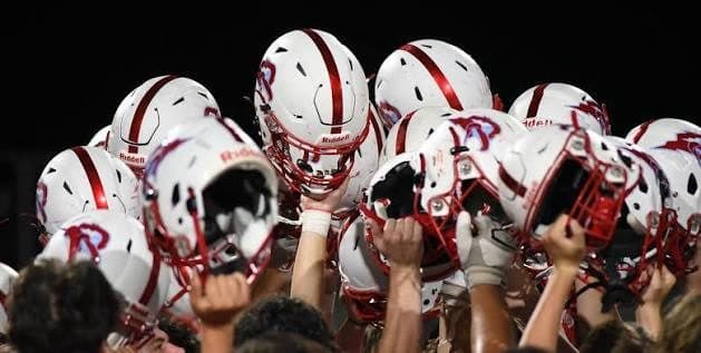 Football players lean into a helmet huddle