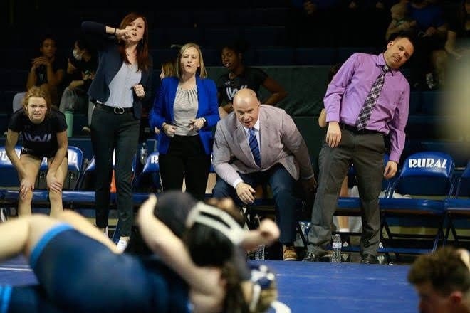 Washburn Rural coaches shouting instructions from the edge of the mat during a girls wrestling match