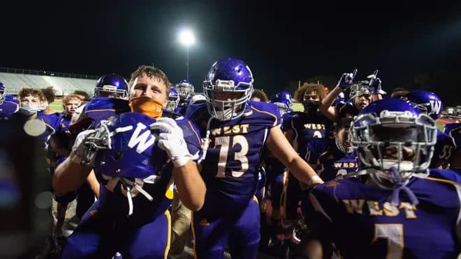 Football players celebrating together after a game under stadium lights